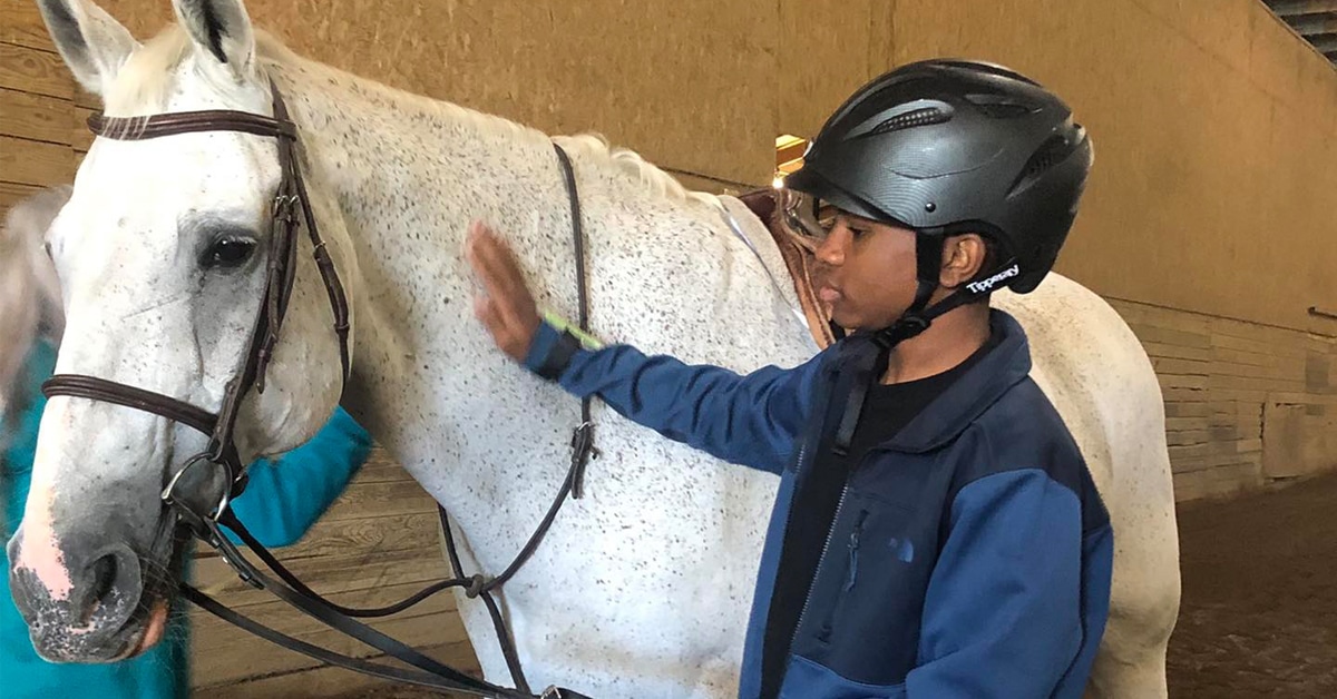 A boy patting a horse.