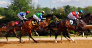 A group of horses racing on a dirt track.