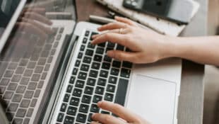 A woman's hands typing on a laptop.