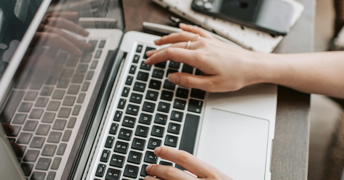 A woman's hands typing on a laptop.