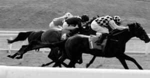Black-and-white image of horses racing.