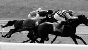 Black-and-white image of horses racing.