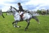 A woman riding a grey horse.