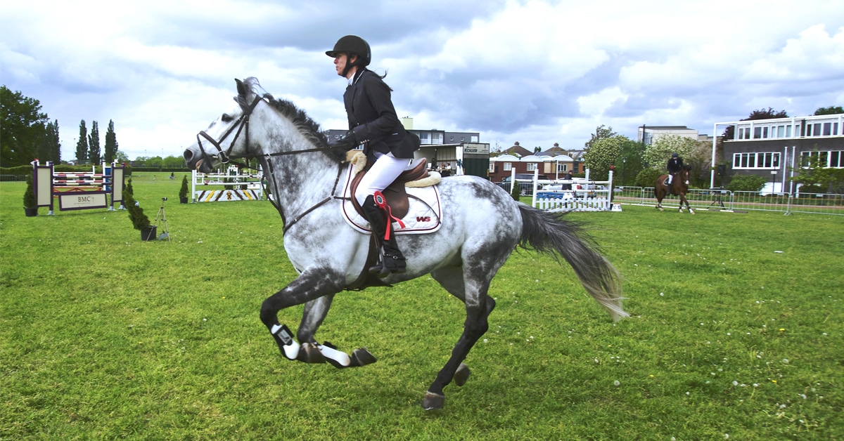 A woman riding a grey horse.