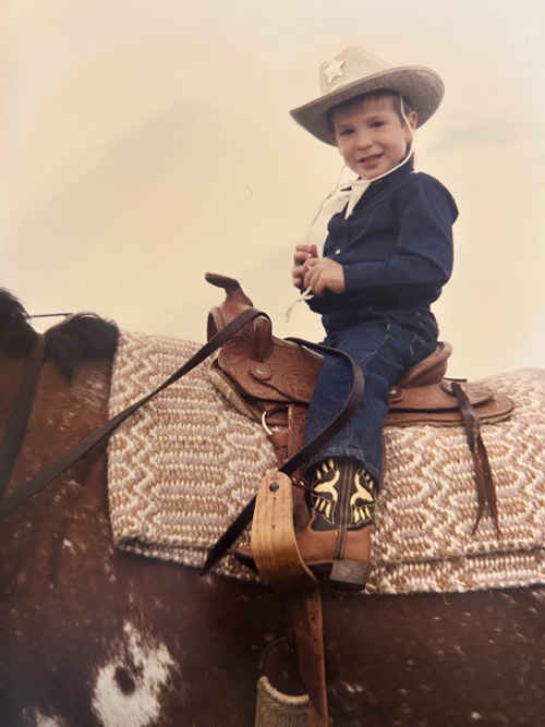 A little boy sitting on a horse in a western saddle.